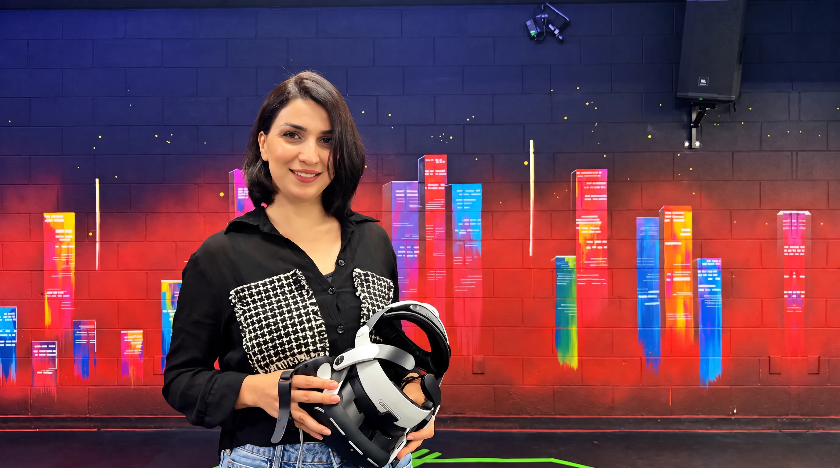 Owner standing in front of a branded arena wall, holding a VR headset